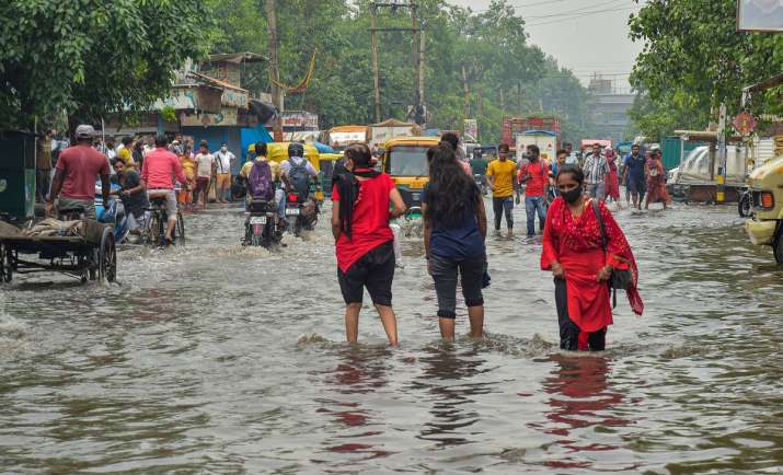 Commuters wade through a waterlogged street after rain at