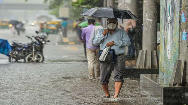 A man carries an umbrella as he walks on a waterlogged road