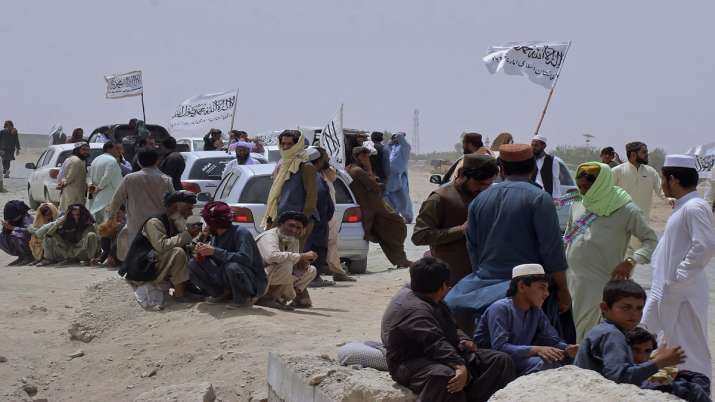 People with the Taliban's signature white flags wait for