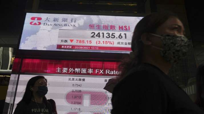 People pass in front of the bank's electronic board, which shows Hong