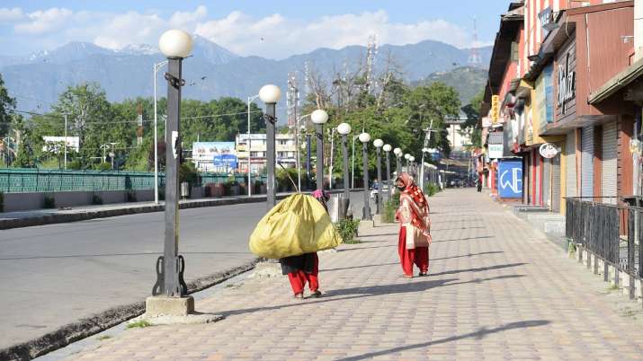 Workers walk on a pavement during lockdown imposed in Jammu