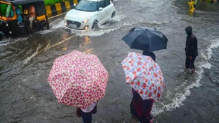 Commuters wait to cross a waterlogged street as vehicles