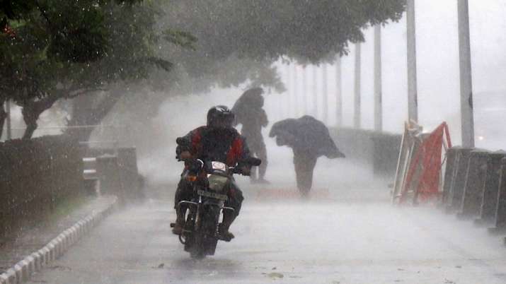A man rides a bike during heavy rain near Marina Beach, in