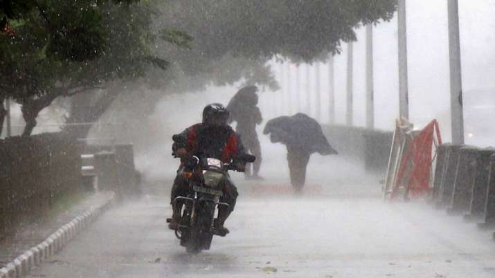 A man rides a bike near Marina Beach during heavy rain, in