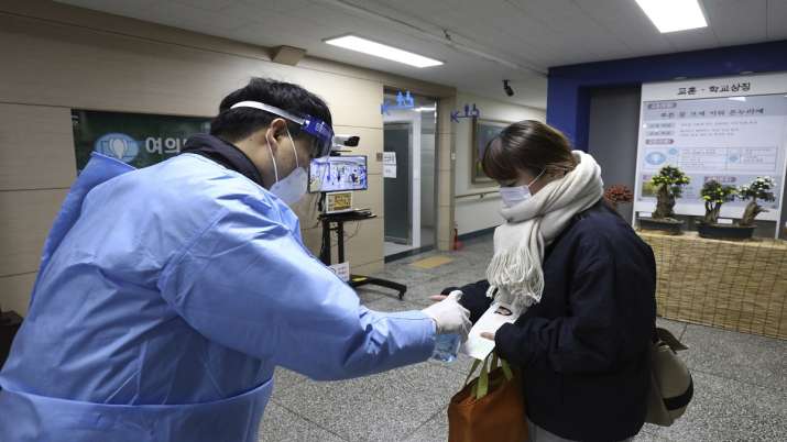 Teacher giving hand sanitizer to South Korean student