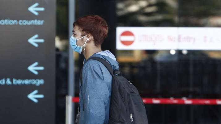 A man wearing a face mask walks at an airport. Nations