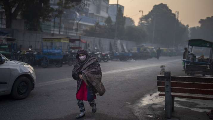 An Indian woman draped in a shawl walks on a cold morning