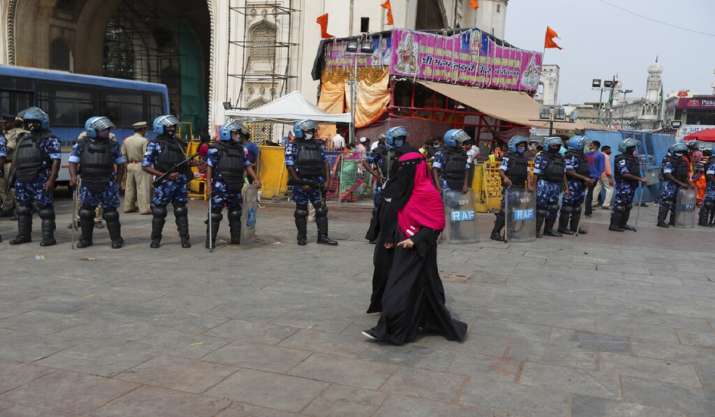 Indian Muslim women walk past paramilitary soldiers