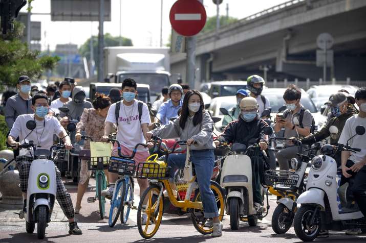 Commuters wearing face masks wait at an intersection in the