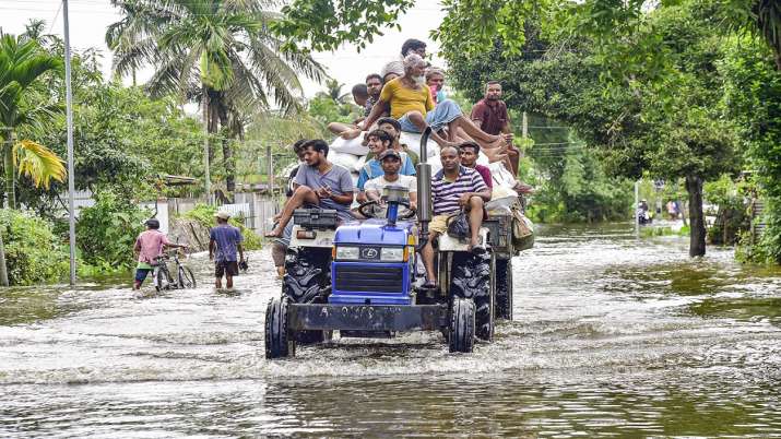 Commuters use a tractor to wade through a flooded street,