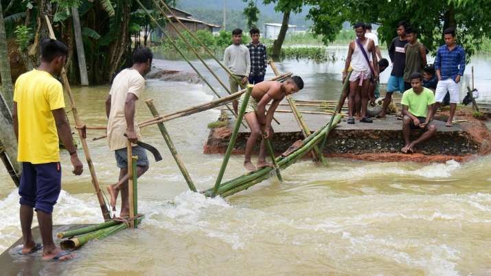 India Tv - Villagers build a makeshift bamboo bridge after flood waters washed away a section of road in a village in Goalpara district of Assam state