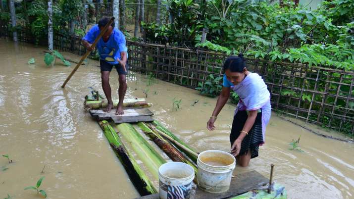 India Tv - Villagers use a banana raft to cross a flooded street, in Nagaon district of Assam, Sunday, June 19, 2022.