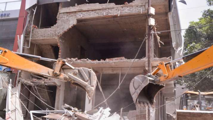 Workers use bulldozers to demolish illegal buildings, a
