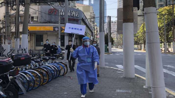 A worker in protective gear holds a sign which reads 