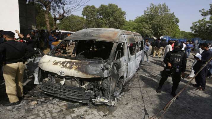 Pakistani investigators examine a burned van at the site of