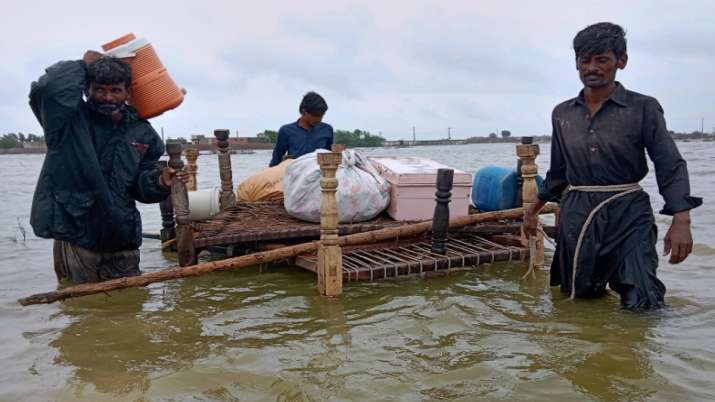India Tv - People use a cart to salvage usable items from their flood-hit homes while they cross a flooded area to reach in higher location, in Tando Jan Muhammad, in southern Pakistan. 