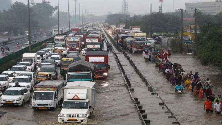 India Tv - Passengers pass through waterlogged Delhi-Gurugram Expressway and its service road after rain in Gurugram