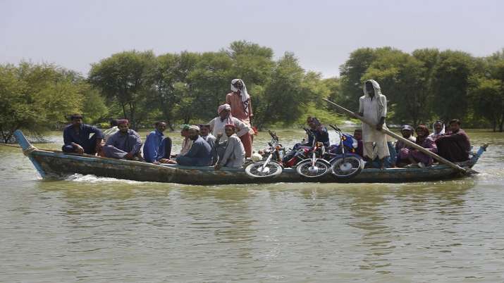 India Tv - Villagers with their belongings cross a flooded area on a boat on September 23, 2022, in Dadu district of Pakistan's southern Sindh province.