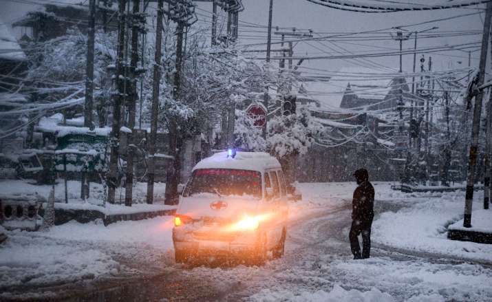 India Tv - Ambulans bergerak perlahan di jalan yang tertutup salju saat hujan salju di Srinagar.