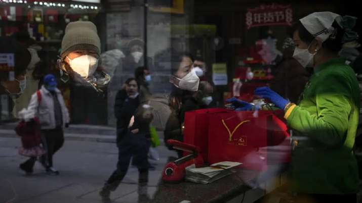 India Tv - People are reflected on a window panel as visitors wearing face masks buy tea products in Qianmen, a popular tourist spot in Beijing. 