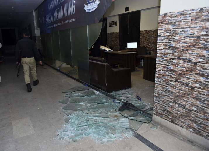 India Tv - A police officer walks past a damage area after security forces conducting operation against attackers at a police headquarters, in Karachi, Pakistan