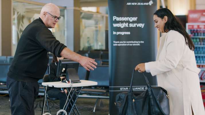 India Tv - A woman gives her bag to a staff member to be weighed before a flight in Auckland, New Zealand.