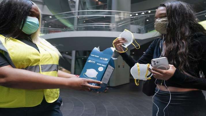 India Tv - MTA employee Shanita Hankel handing out masks to commuters at the entrance of a subway station in New York. 