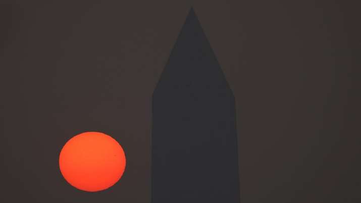 India Tv - The sun rises behind the Washington Monument and a thick layer of smoke in Washington. 