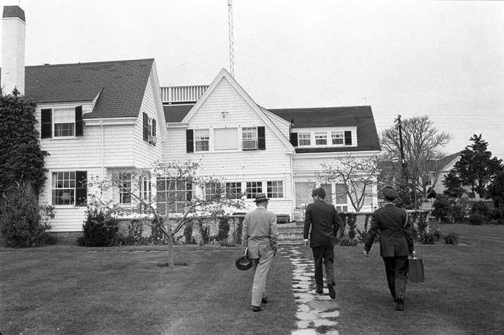 India Tv - In this photo obtained by the National Security Archive from the John F. Kennedy Presidential Library, White House military aide Gen. Chester Clifton carries the Presidential Emergency Satchel with Kennedy and David Powers, approaching the 