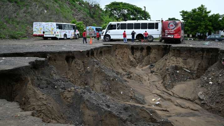 India Tv - People walk near a landslide caused by heavy rains in Veracruz, Mexico.