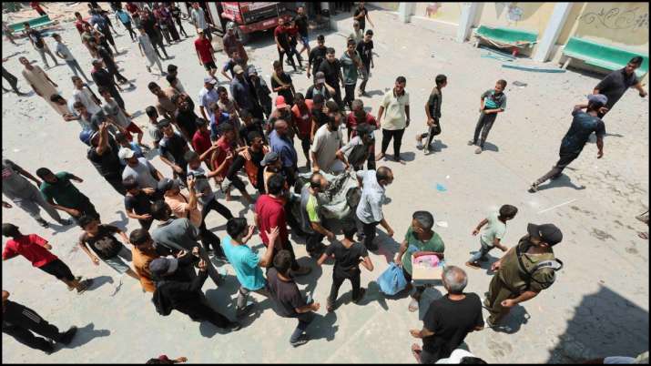 इंडिया टीवी - इजरायली हमले के बाद विस्थापित लोगों को आश्रय देने वाले स्कूल में एक घायल को ले जाते हुए फिलिस्तीनी।