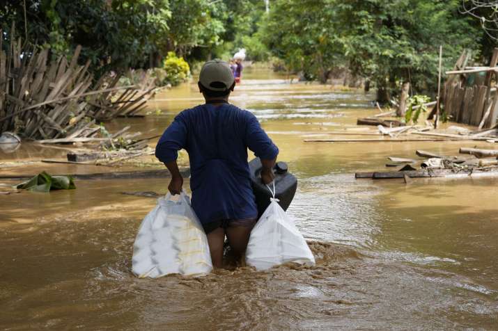 India Tv - Local resident carrying food wade through a flooded road in Naypyitaw