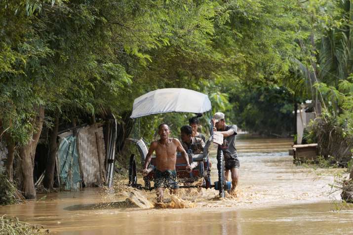 India Tv - Local residents carrying food on their cart wade through a flooded road in Naypyitaw, Myanmar