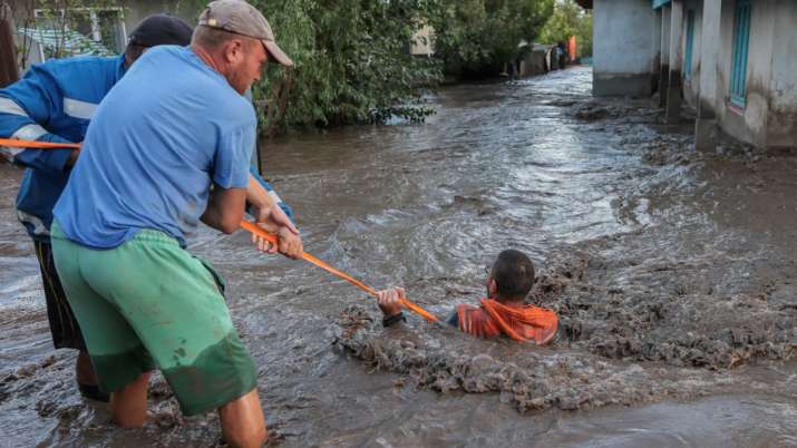 India Tv - Locals and rescuers pull a man through flood water after heavy rain triggered flooding in Romania.