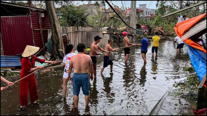 India Tv -  People remove fallen trees following the impact of Typhoon Yagi in Vietnam.