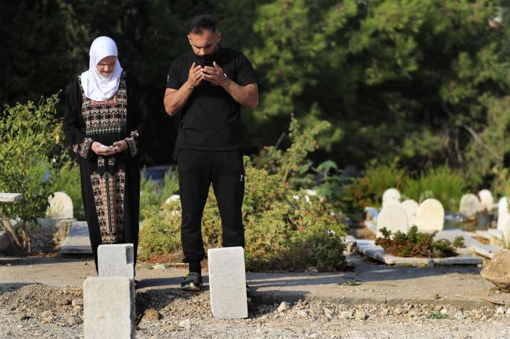 India Tv - Jamileh, left, and Achraf Ramadan pray at a cemetery for their relatives who were killed on Sept. 29