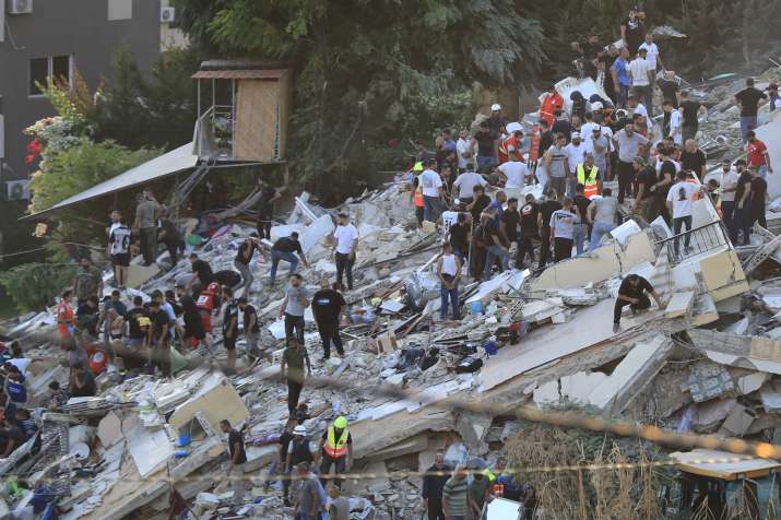 India Tv - eople and rescue workers search for victims after an Israeli airstrike hit two adjacent buildings