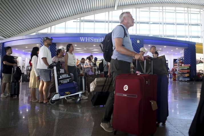 India Tv - Passengers look at a flight information board after a number of flights are cancelled due to the eru