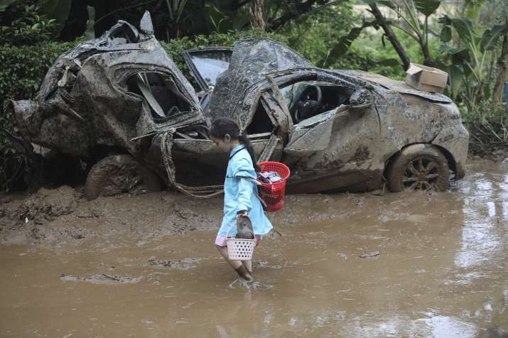 India Tv - A young girl walks past the wreckage of a car after a landslide killed a number of people and left s