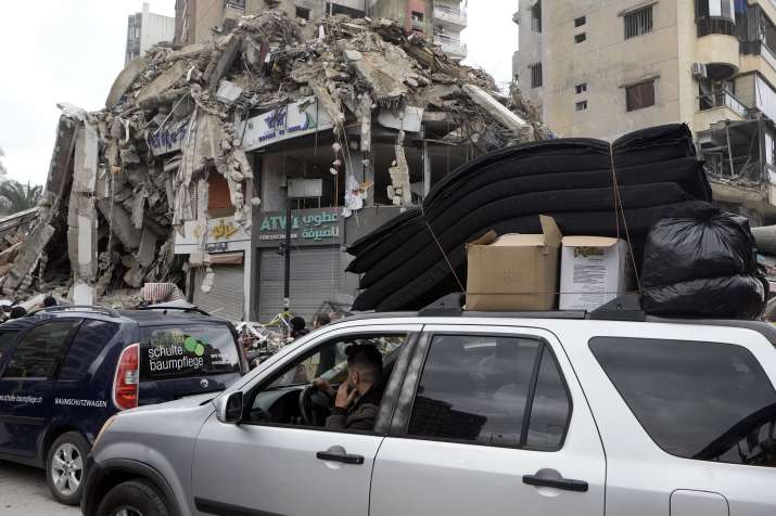 India Tv - People gather as vehicles drive near damaged buildings, in Beirut's southern suburbs, after a ceasef