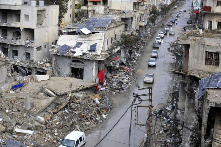 India Tv - People gather as vehicles drive near damaged buildings, in Beirut's southern suburbs, after a ceasef