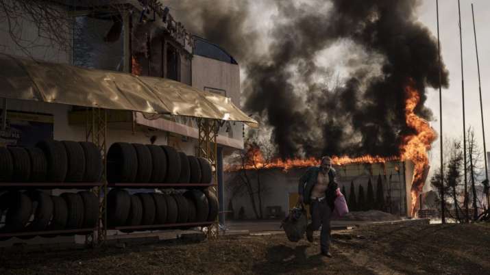 India Tv - A man runs while recovering items from a burning shop following a Russian attack in Kharkiv, Ukraine