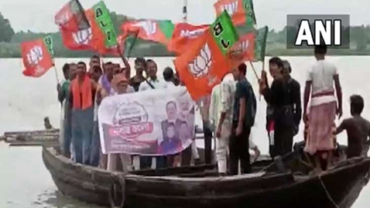 A group of BJP workers uses a boat to cross Tribeni river,