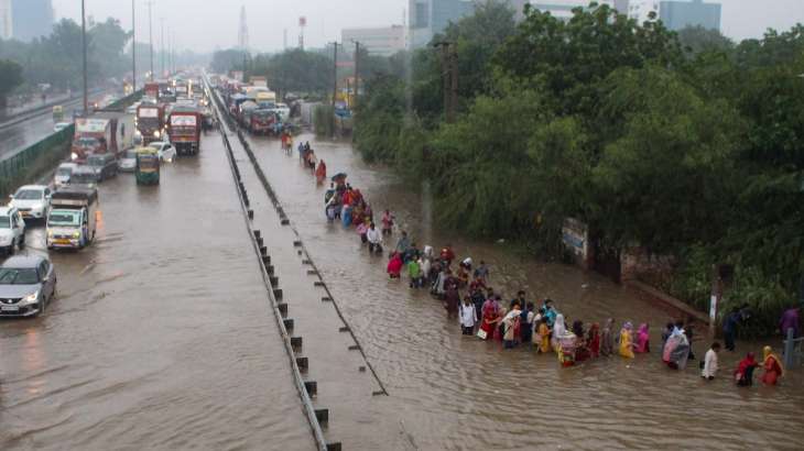 Commuters wade through the waterlogged Delhi-Gurugram