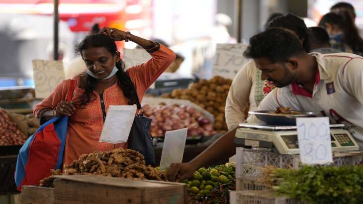 A woman bargains as she buys vegetables at a market place