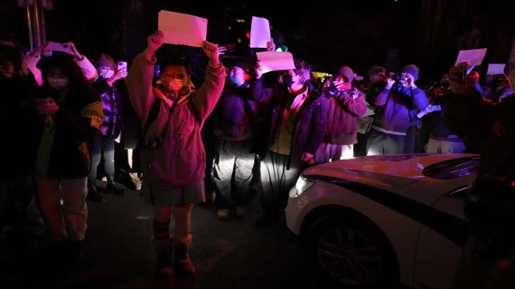Protesters hold up blank papers and chant slogans as they
