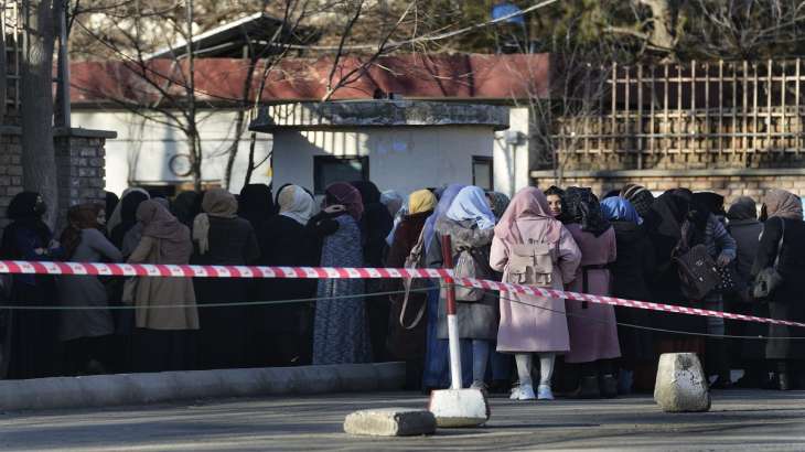 Afghan students queue at one of Kabul University's gates in