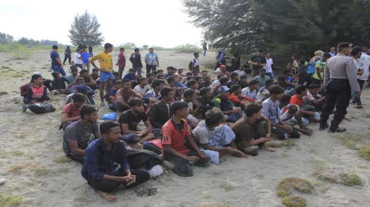 Ethnic Rohingya people sit on the beach after disembarking
