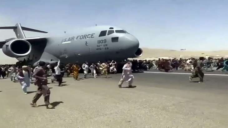 Hundreds of people run alongside a U.S. Air Force C-17