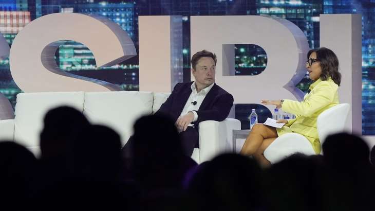 Twitter CEO Elon Musk, center, speaks with Linda Yacarino,